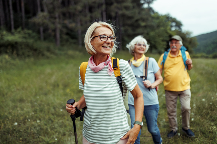 trois seniors souriants sac au dos se promènent dans la nature