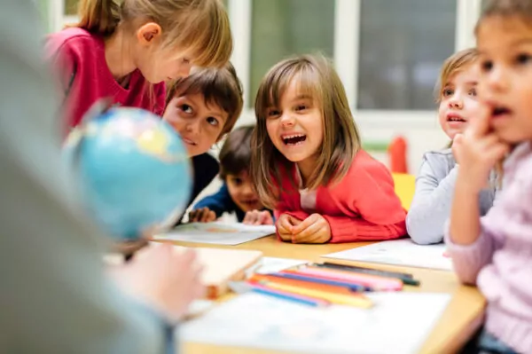 Enfants riant autour d'une table lors d'un moment partagé à l'école