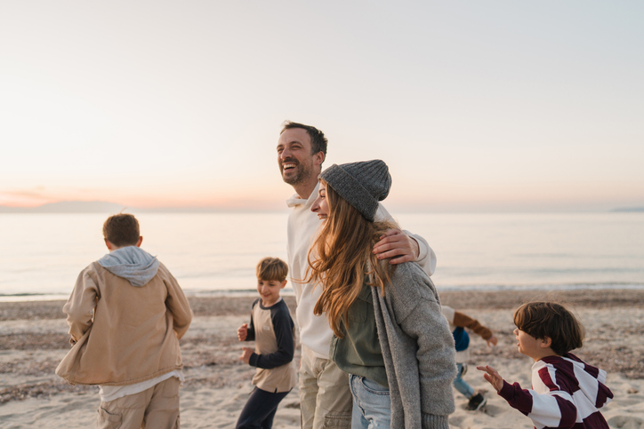 une famille se promène sur la plage, un couple et 4 enfants