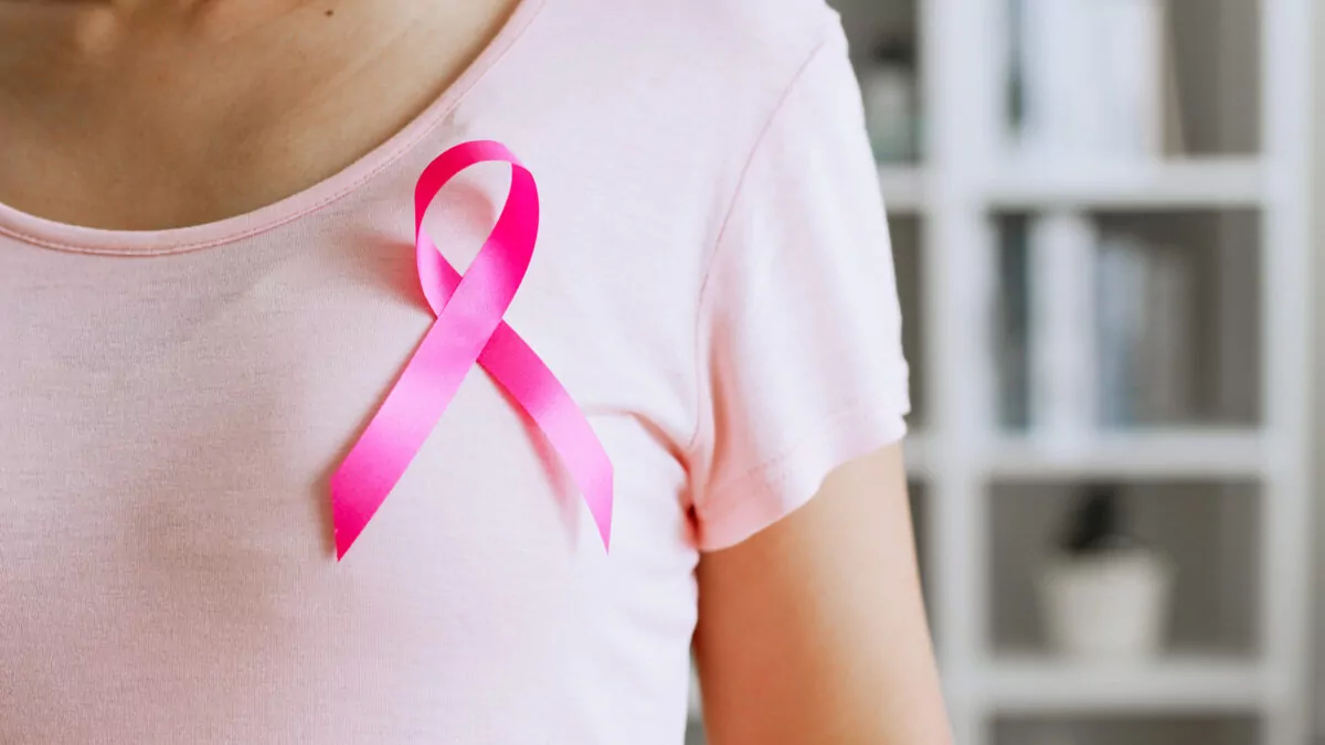 Femme portant un tee-shirt rose avec le symbole d’Octobre Rose, campagne de sensibilisation au dépistage du cancer du sein.