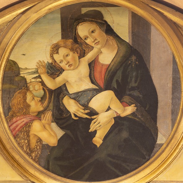 Peinture ancienne représentant la Vierge Marie assise, tenant l’Enfant Jésus sur ses genoux, tandis qu’un jeune saint aux cheveux bouclés prie à ses côtés, dans un cadre circulaire doré.