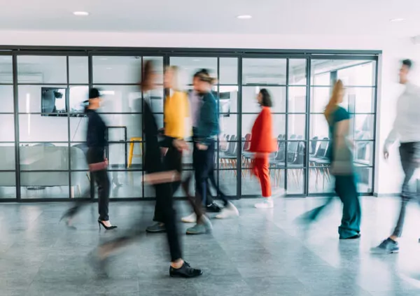 Des personnes se croisent dans un couloir d'entreprise.