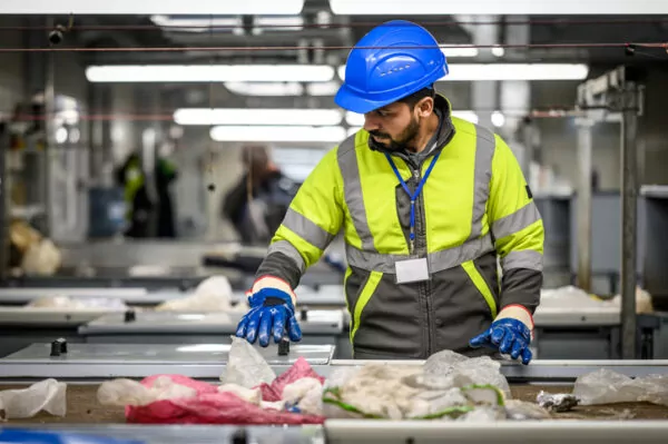 un homme trie des déchets papier sur une chaîne d'usine
