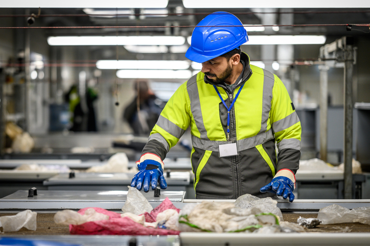 un homme trie des déchets papier sur une chaîne d'usine