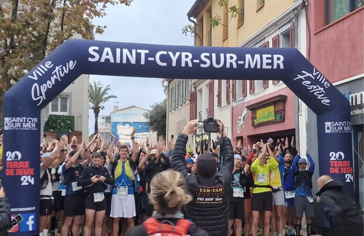 Des coureurs réunis sur la ligne de départ du trail à Saint-Cyr-sur-Mer, sous une arche gonflable aux couleurs de la Ville.